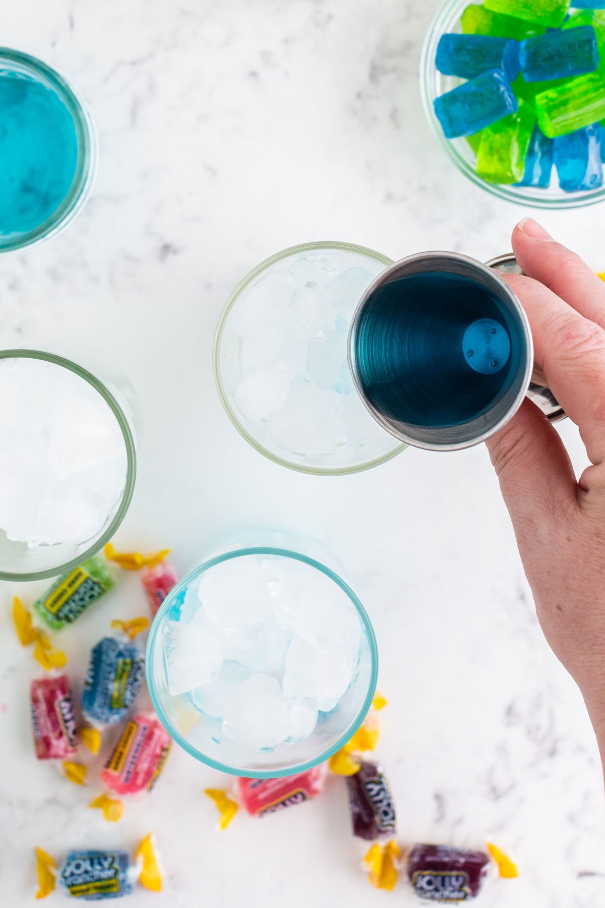 Blue Jolly Rancher vodka poured into glass of ice.