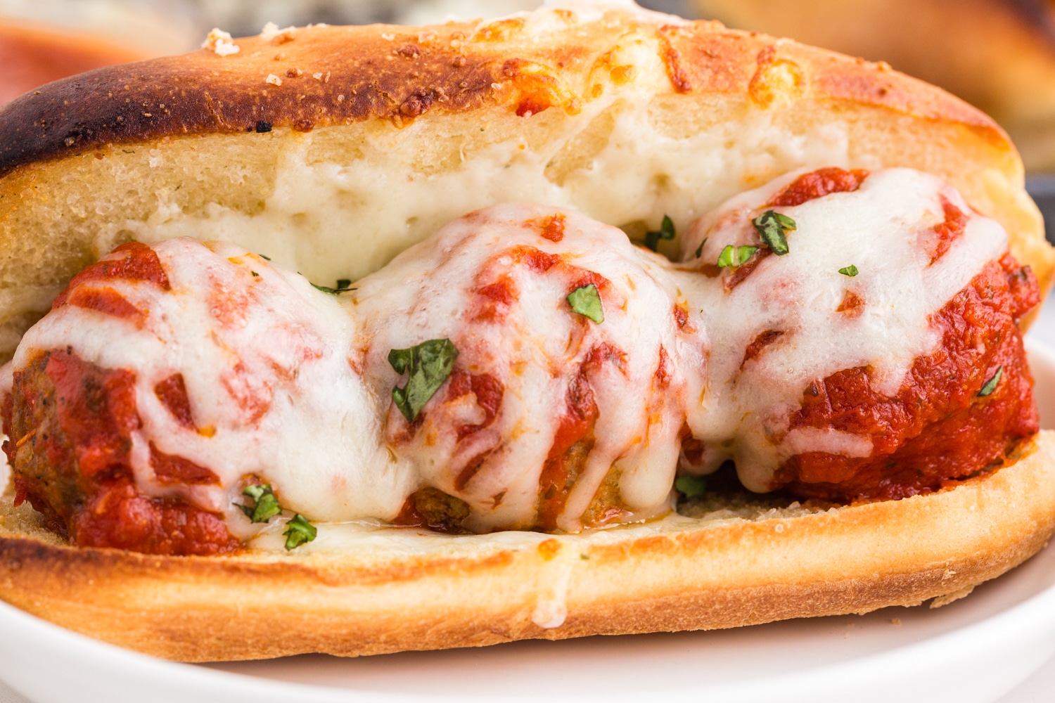 Close up of Meatball Sub on a cake plate on a marble countertop.