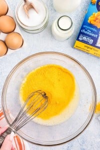 whisking cheese powder into cream mixture in glass bowl