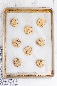 scoops of Oatmeal Chocolate Chip Cookie dough on baking tray lined with parchment paper