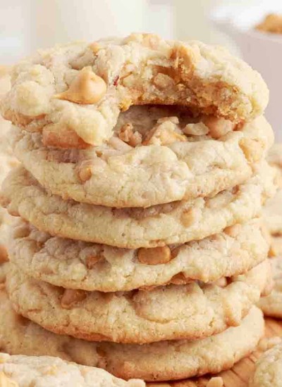 a stack of chewy butterscotch toffee cookies with one that has a bite taken out