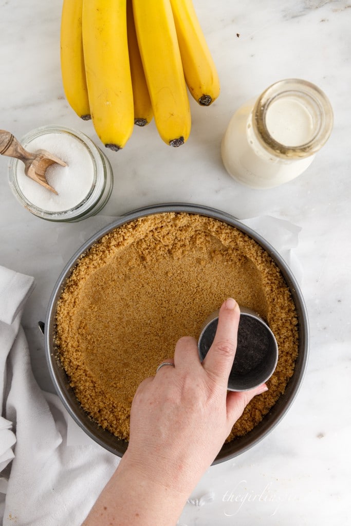 smoothing out graham cracker crust in a pan