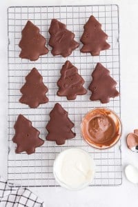 chocolate coated christmas trees on cookie sheet with bowls of melted milk and white chocolate