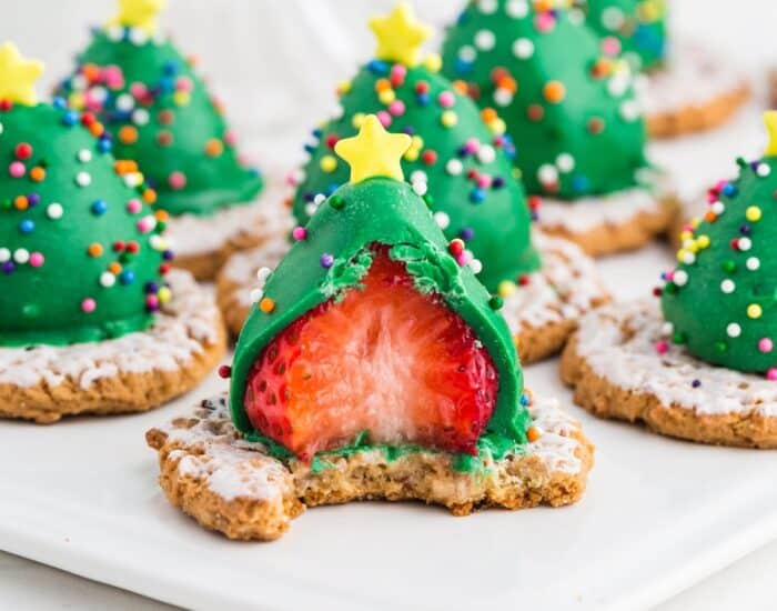 Green chocolate covered strawberry placed upside down on a frosted oatmeal cookie, with sprinkles and a star sprinkle on top.