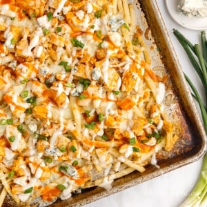 buffalo fries with chicken fresh out of the oven on a baking sheet topped with blue cheese crumbles
