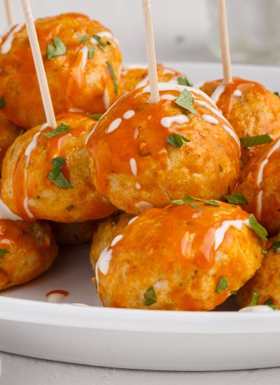 buffalo chicken meatballs mounded on white platter with toothpicks for serving