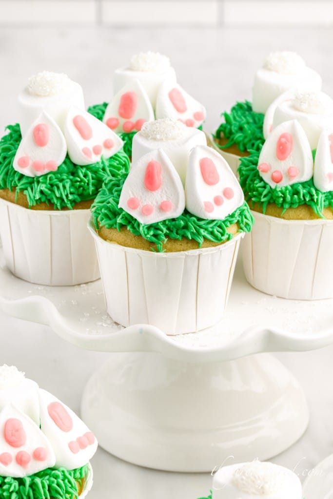 several bunny butt cupcakes on a white cake stand