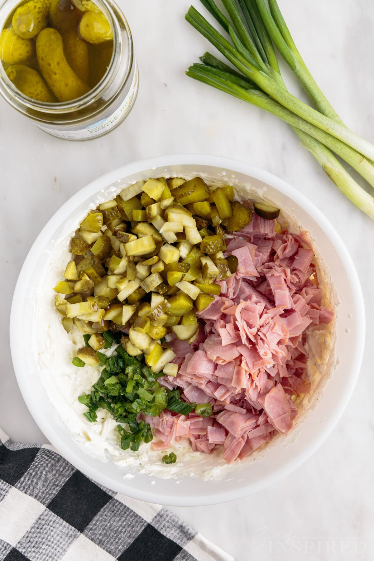 Chopped ham, chopped dill pickles, and green onions piled in bowl with cream cheese mixture.