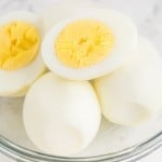 air fryer hard boiled eggs cut in half and placed in a clear glass bowl on top of a marble surface