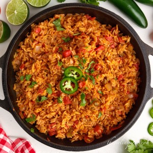 top view of mexican rice in cast iron skillet with red linen and jalapeno garnish