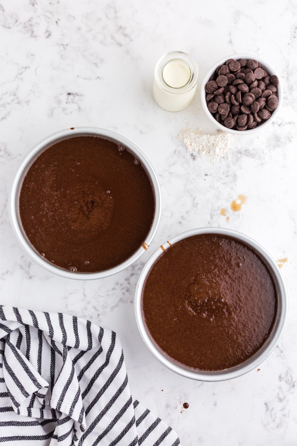 Two round cake pans with baked chocolate cake in them.