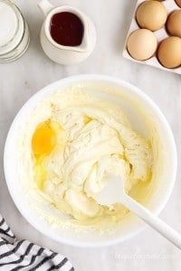 spatula mixing in one egg to bowl of cheesecake mixture.