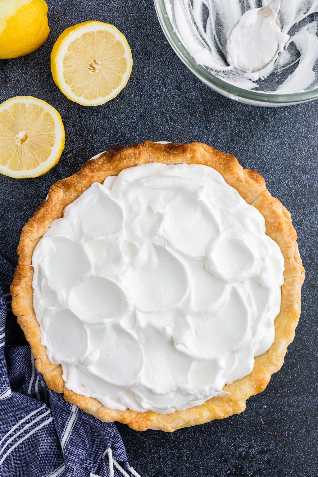 unbaked meringue swirled over the top of the pie filling with lemons and blue linen