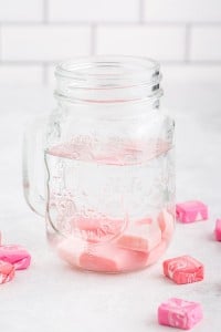 Glass jar on a white marble countertop with Starburst candies and vodka inside