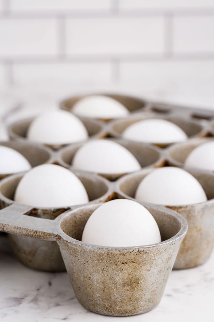 eggs placed in a 12-cup muffin tin, placed on a white marble surface