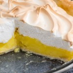 Lemon meringue pie with a slice of pie removed, presented on a clear glass pie dish