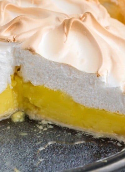 Lemon meringue pie with a slice of pie removed, presented on a clear glass pie dish