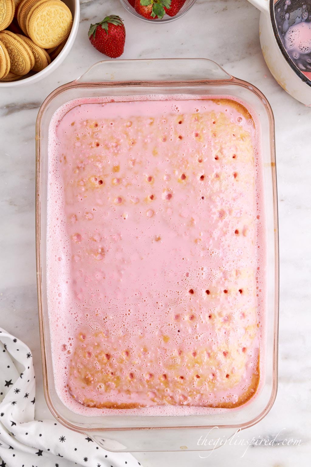 layer of strawberry jello mixture seeping into the holes in the cake.