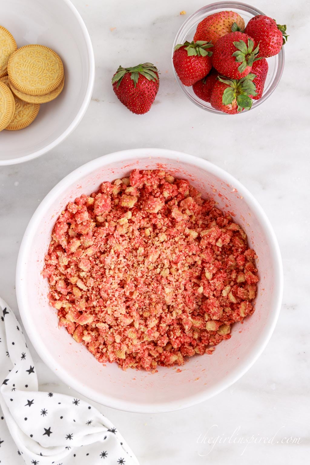 pink tinted cookie crumbs in a white mixing bowl.