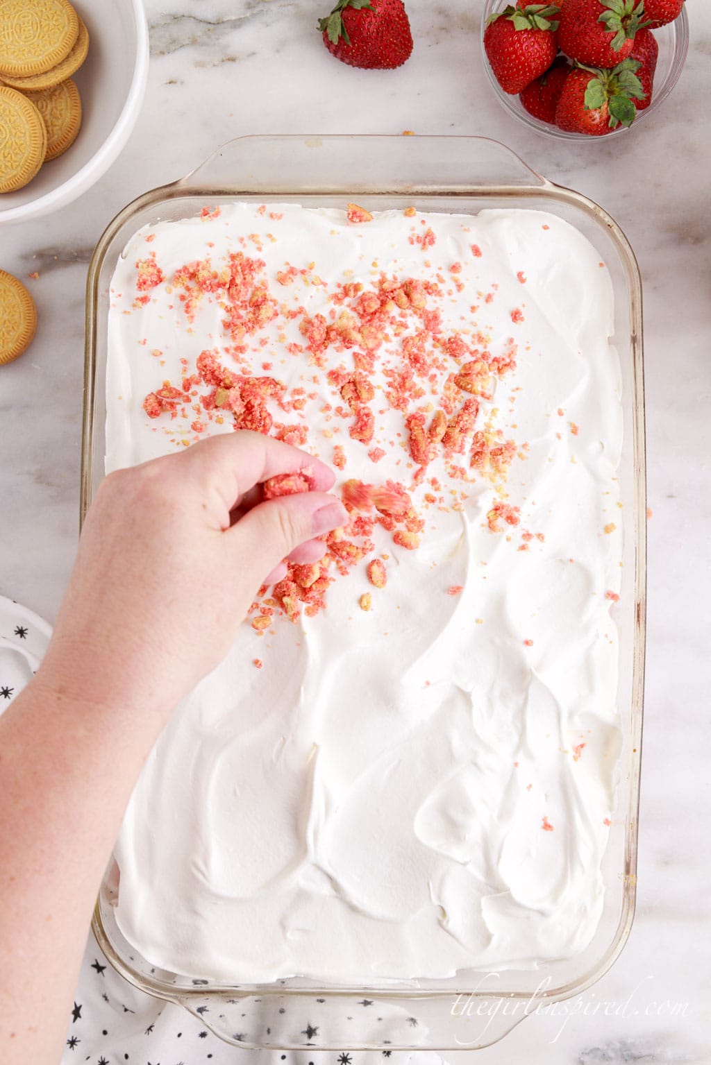 hand sprinkling cookie crumbs over the whipped topping.