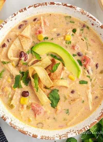 a bowl of crockpot chicken tortilla soup next to cilantro garnish.
