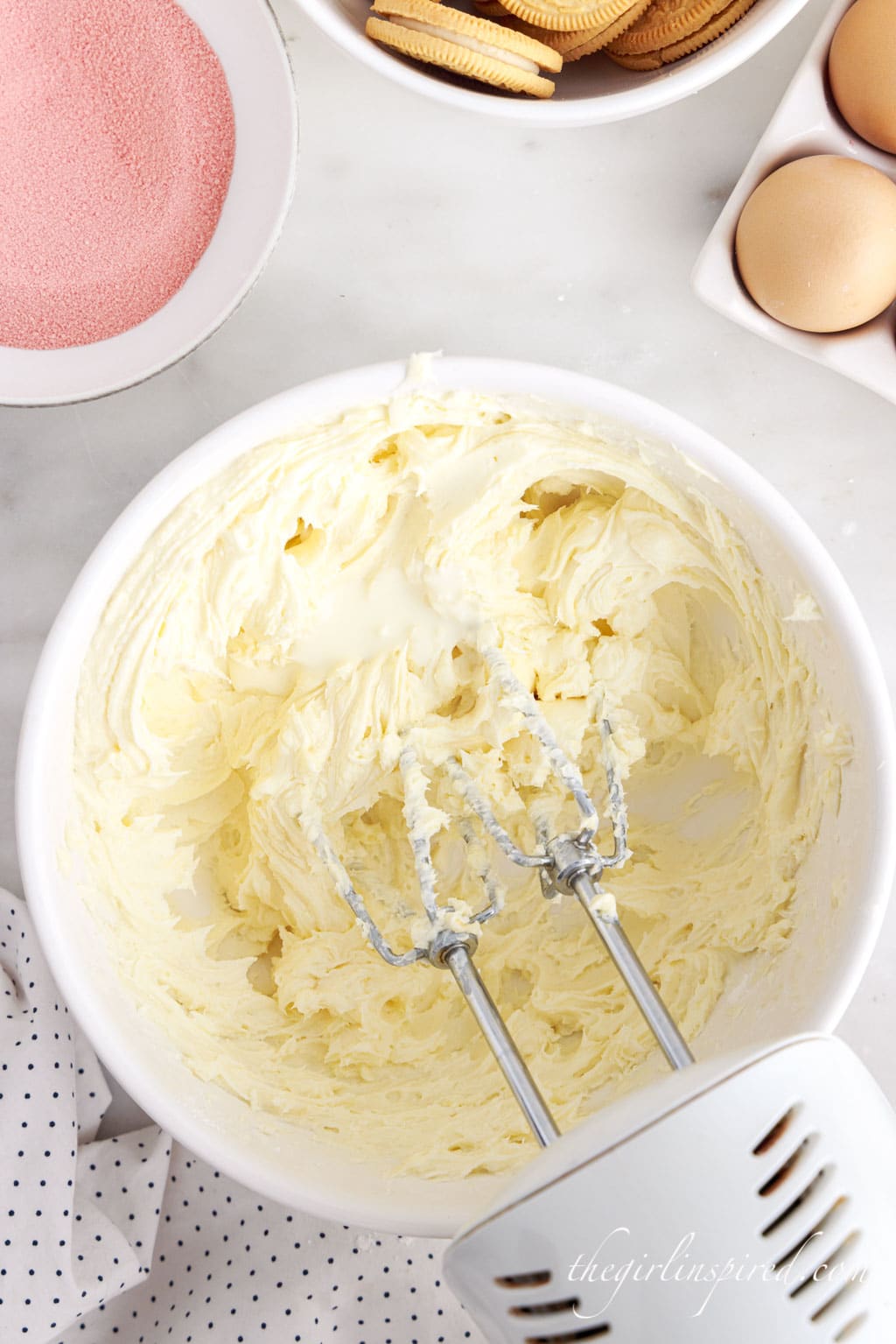 mixing cream cheese frosting ingredients with a hand mixer