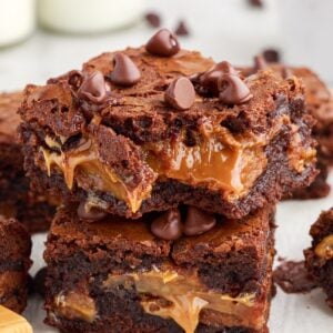 Two caramel brownies stacked on top of each other with caramel oozing out.