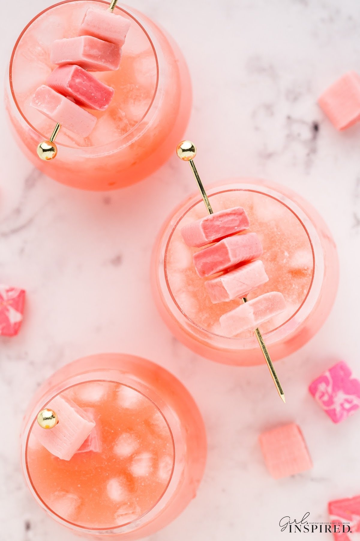 Top view of three wine glasses filled with pink starburst cocktail and garnished with Starburst skewers.