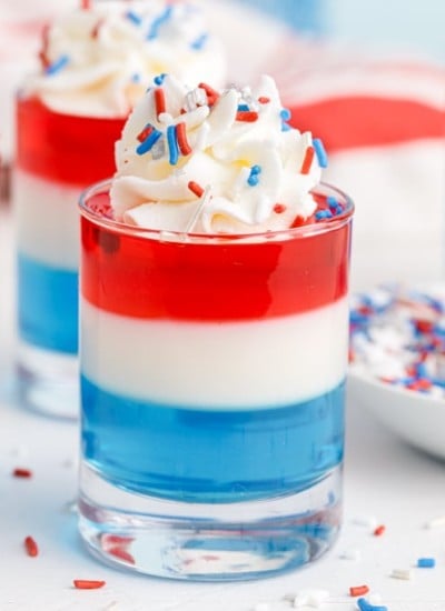 three patriotic jello shots next to a bowl of sprinkles