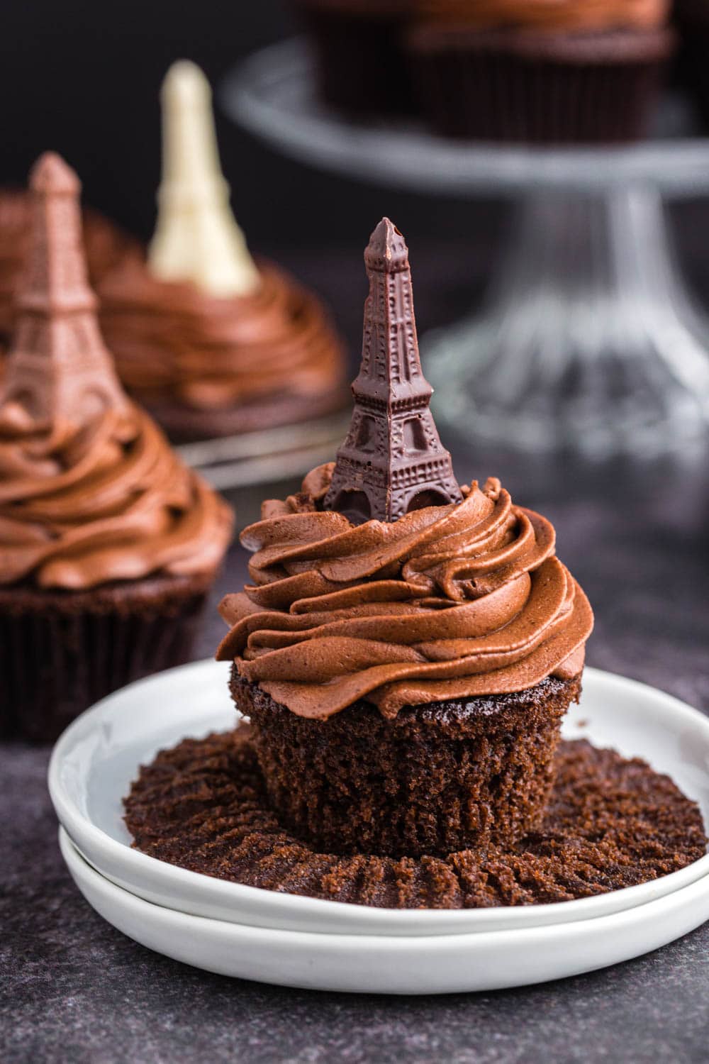 chocolate cupcake piled high with chocolate frosting and a dark chocolate molded Eiffel tower on top.