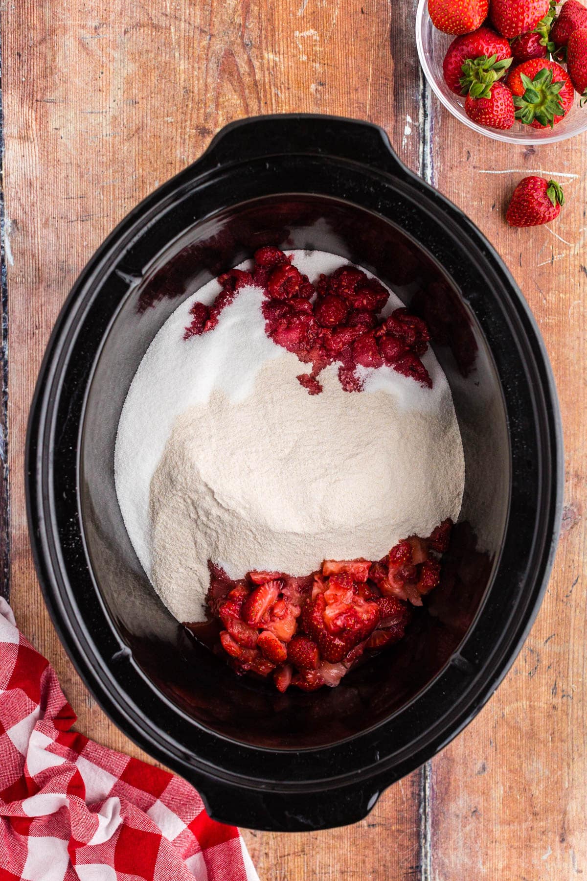 Strawberries, raspberries, pectin and sugar in the crock of a slow cooker.