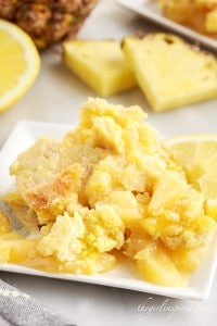 Lemon dump cake on a plate with pineapple in the background.