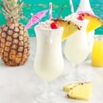 two pina coladas next to a pineapple