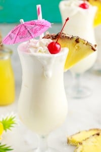 a pina colada with whipped cream, cherry, and a pineapple wedge