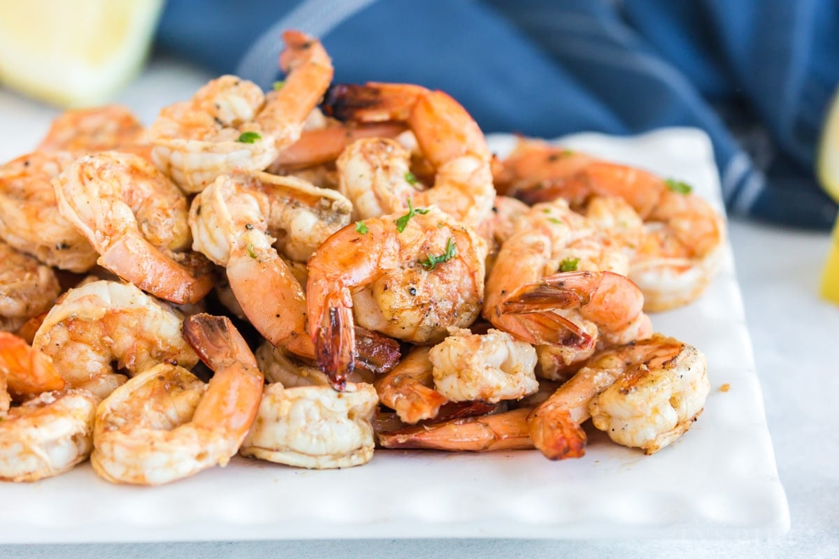 platter of grilled shrimp skewers with the shrimp removed from the kabobs on a platter, with lemon wedges.