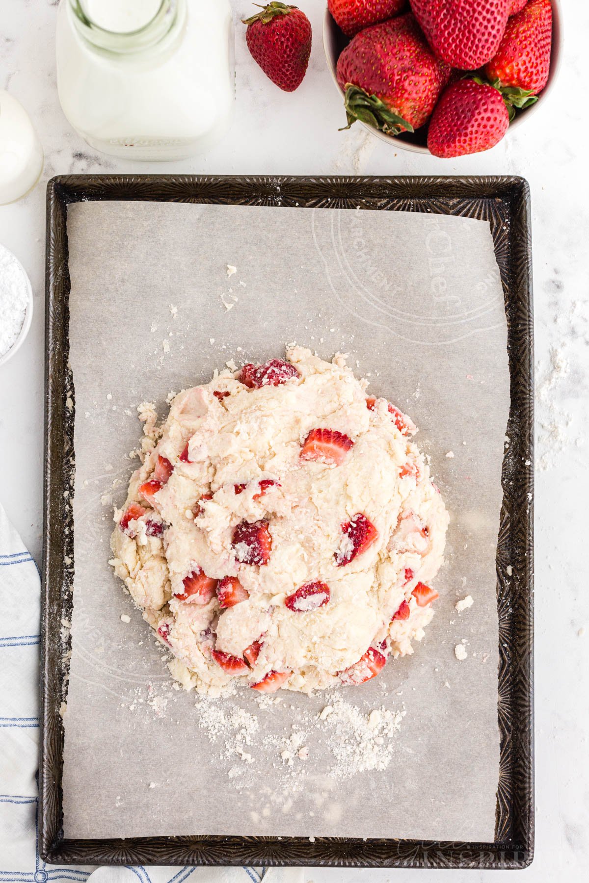 One round of strawberry scone dough patted down on parchment paper-lined baking sheet.