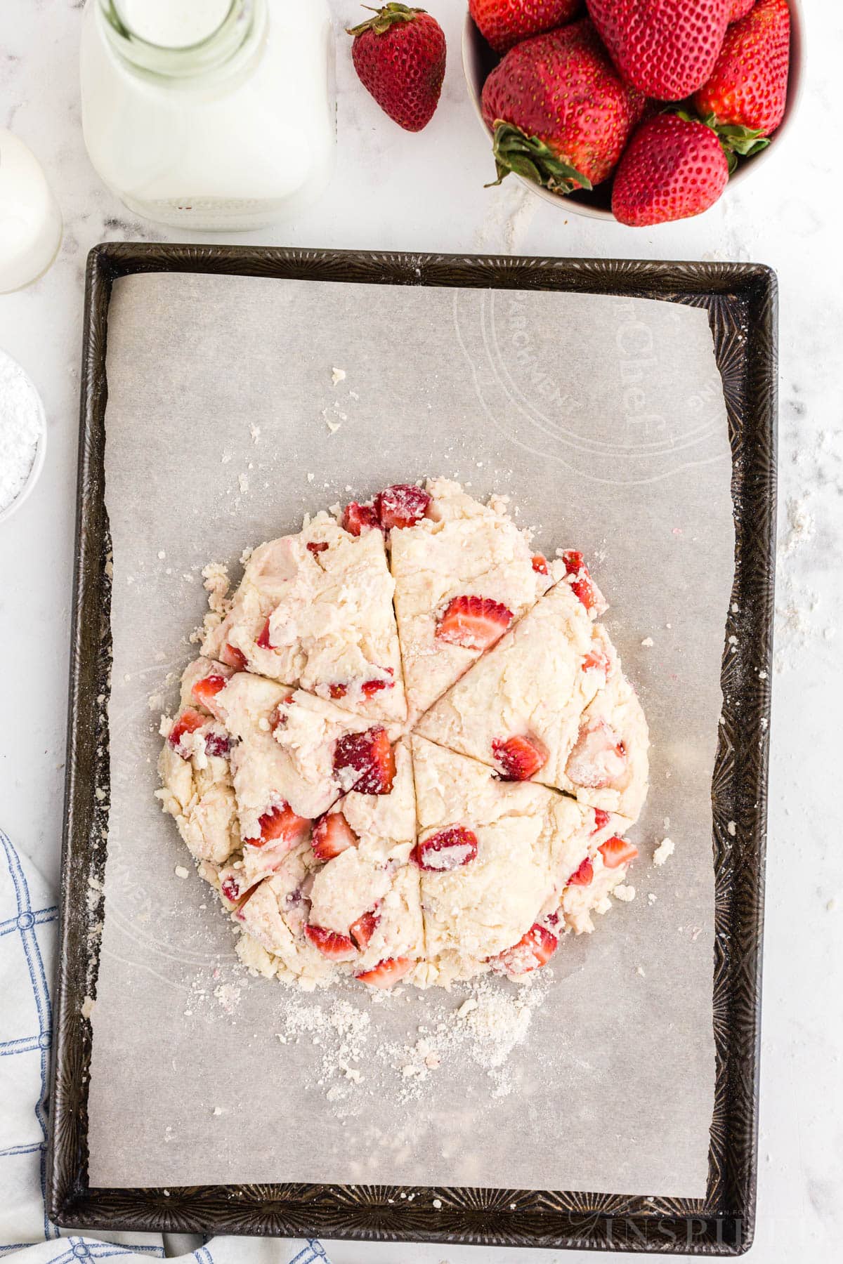 Round strawberry scones dough scored into triangles.