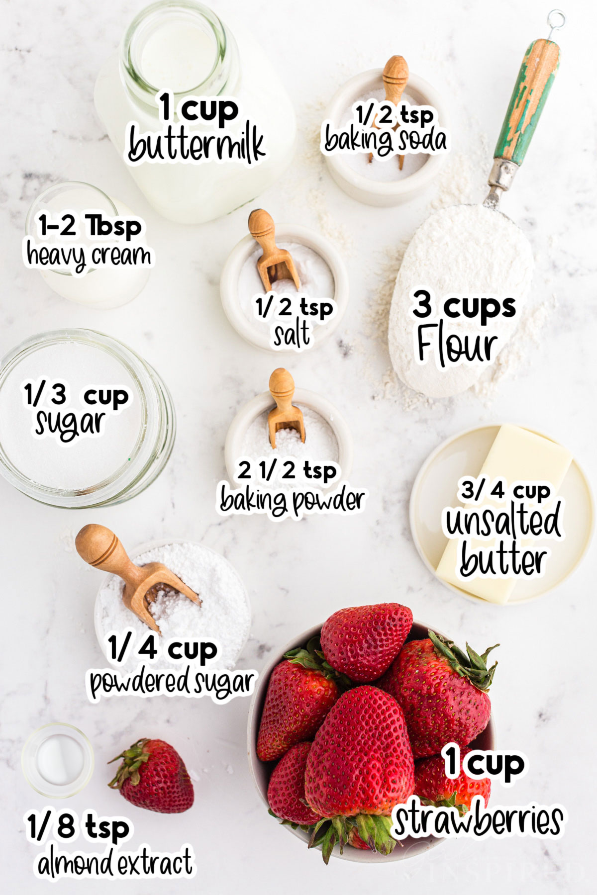 Fresh ingredients for strawberry scones in separate bowls and jars on top of a white marble surface with text amounts and labels.