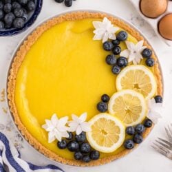 Lemon curd tart topped with editable flowers, blueberries, and lemon slices.