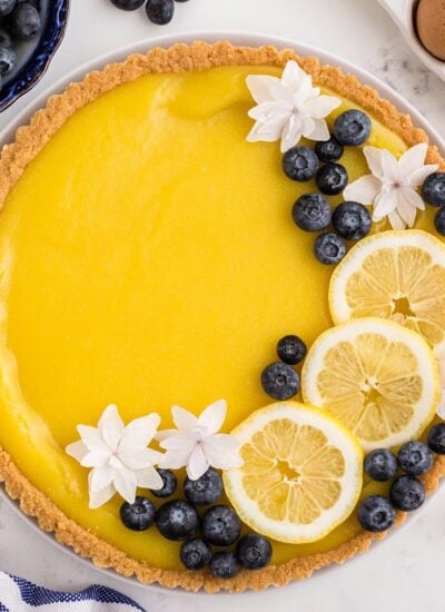 Lemon curd tart topped with editable flowers, blueberries, and lemon slices.