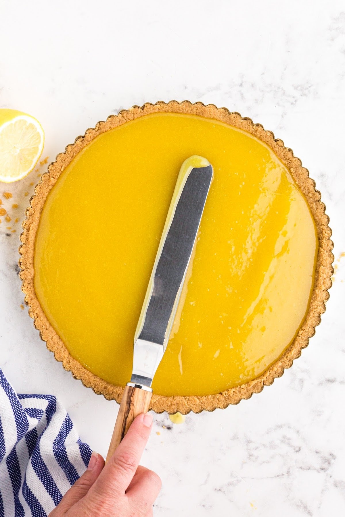 Spreading the lemon curd into the shortbread crust with a spatula. 