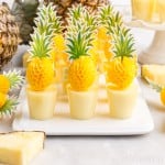 a tray of dole whip jello shots with pineapple paper toppers in each one