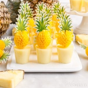 a tray of dole whip jello shots with pineapple paper toppers in each one