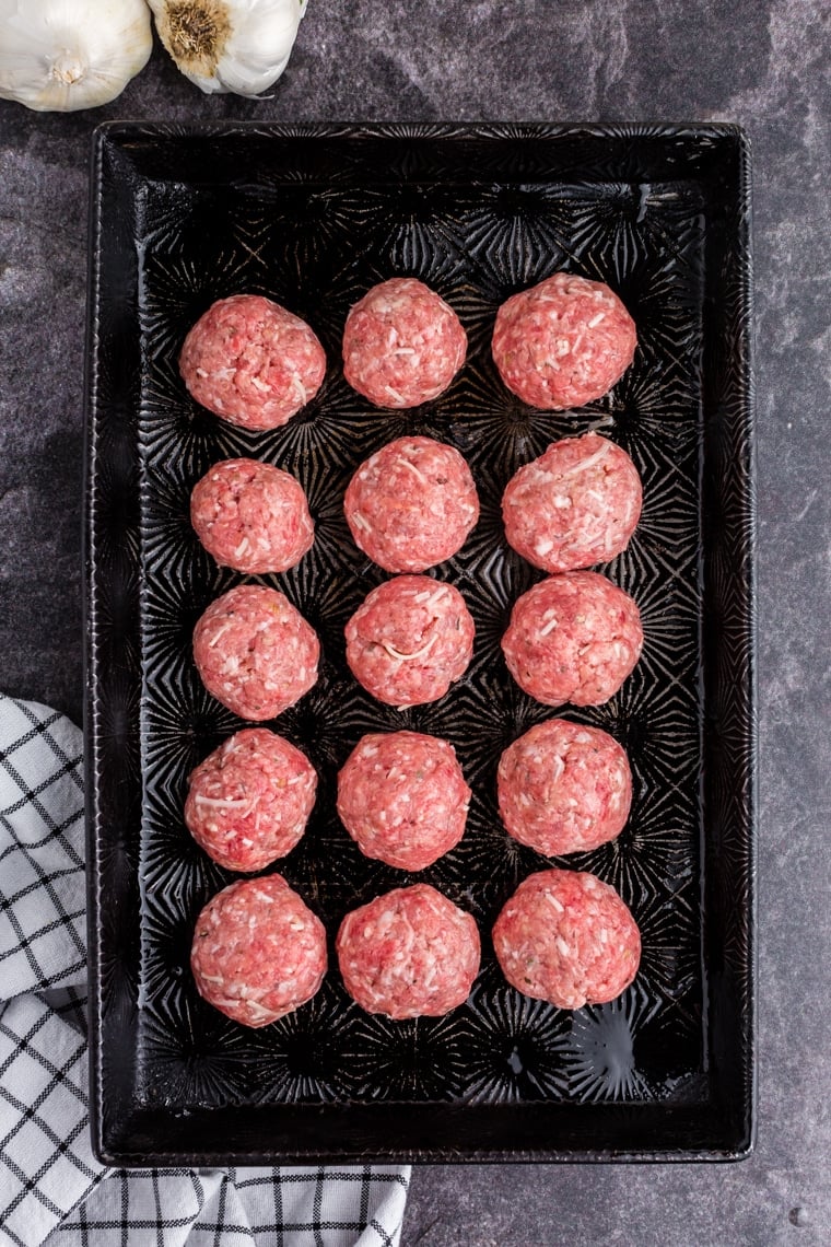 raw meatballs on a baking sheet before going into the oven