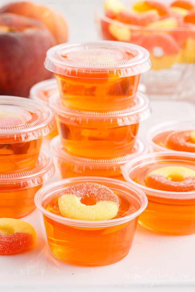 peach jello shots in plastic cups some with lids on and stacked