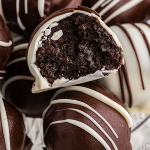 Close up of piled Oreo balls coated in white and dark chocolate, single Oreo ball cut in half with filling exposed