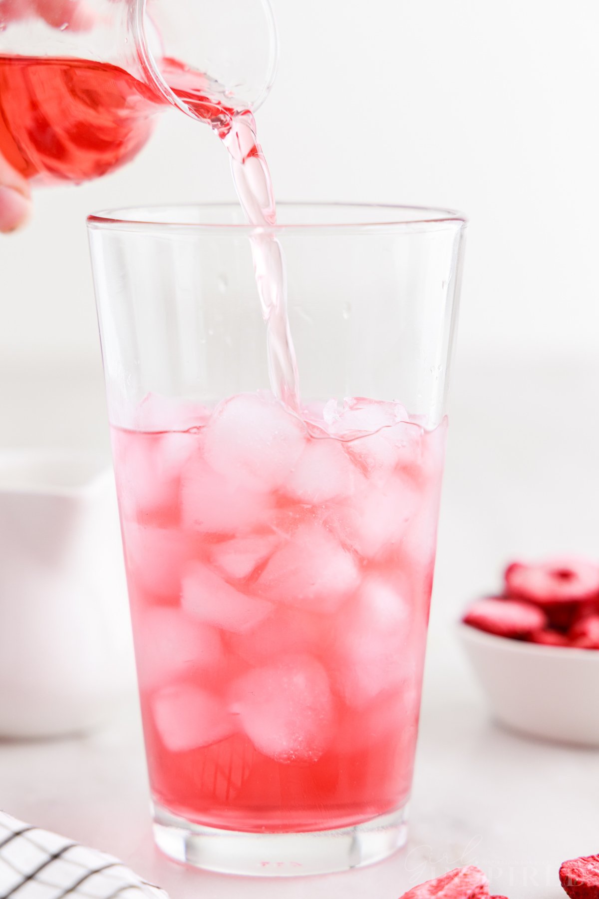 Pink tea poured into glass of ice to make pink drink recipe.