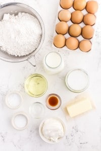 White cupcake ingredients gathered together on a white marble countertop