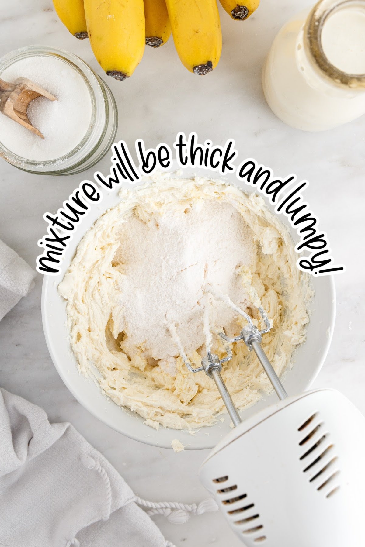 Adding pudding powder to the banana cream cheesecake mixture in mixing bowl with hand beater and text overlay "mixture will be thick and lumpy."