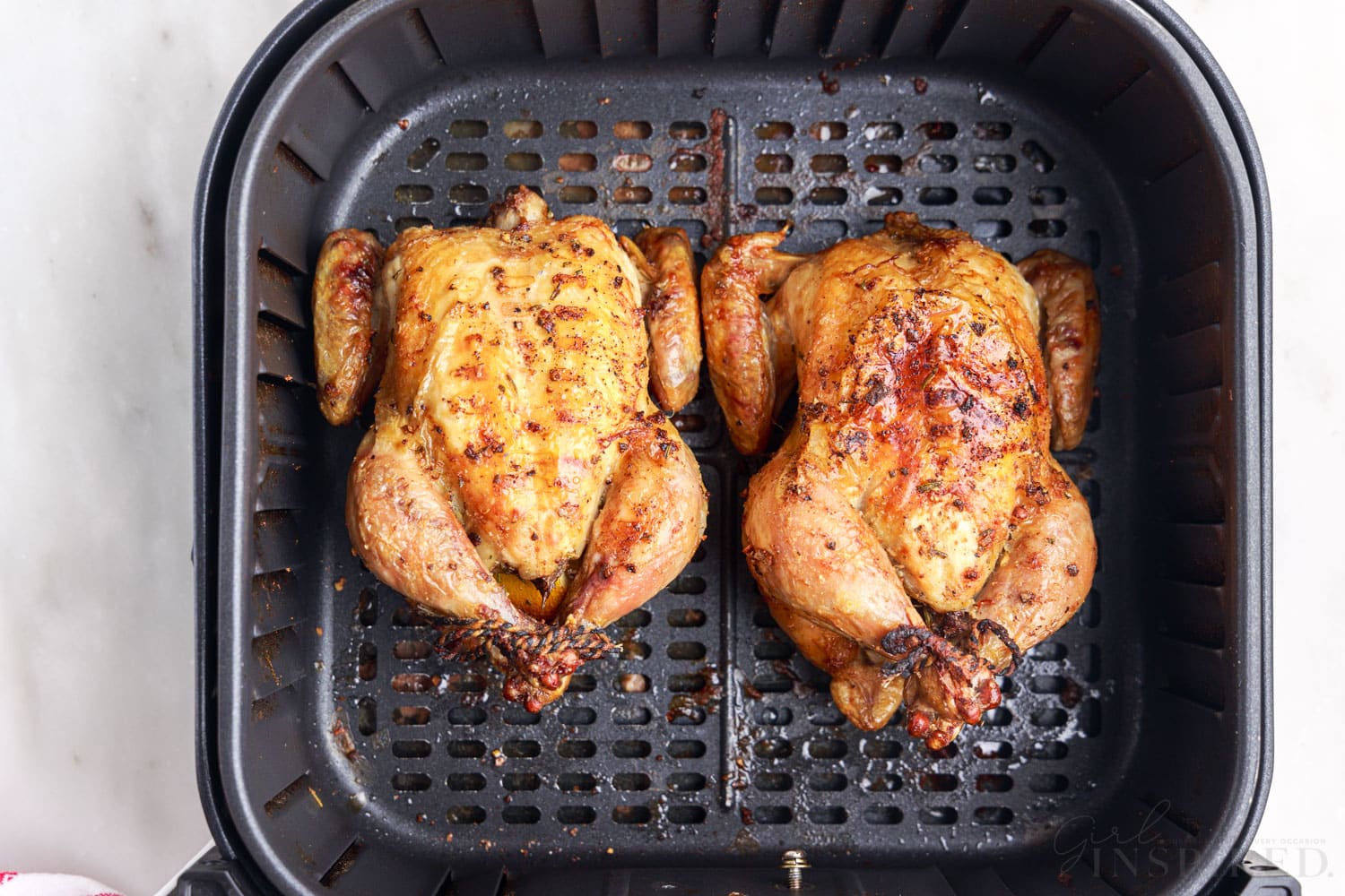 overview of two air fryer cornish hens in an air fryer basket
